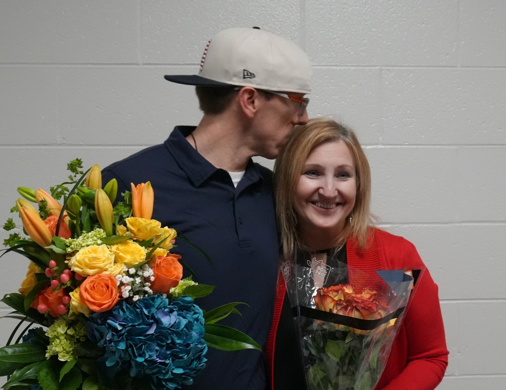 Man kisses top of woman's forehead during celebration.