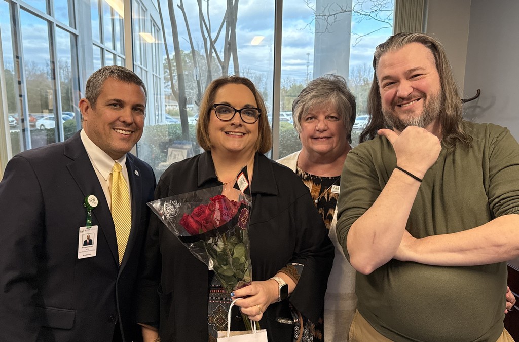 Four people smile together.