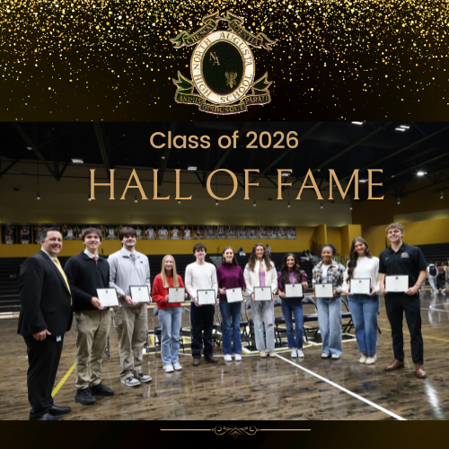 Students posing in gym with awards and principal.