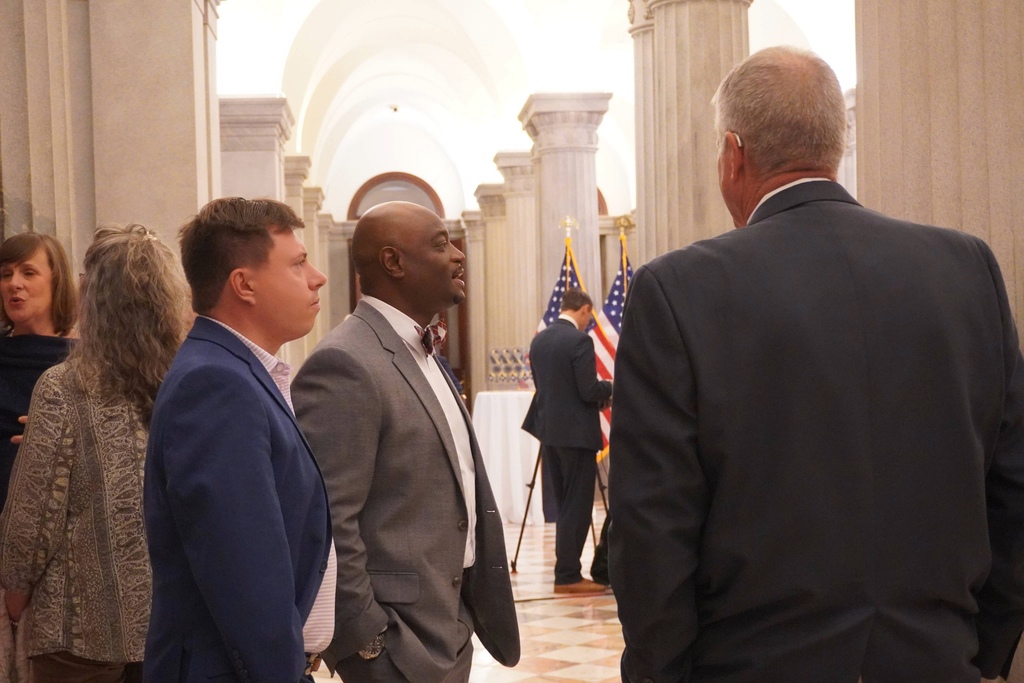 Board member speaking with Dr. Murphy at blue ribbon ceremony.