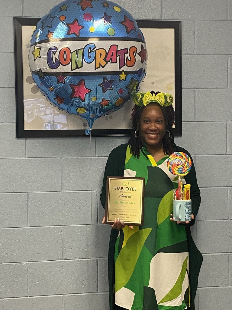 Ms. Clay holding an employee of the month award.
