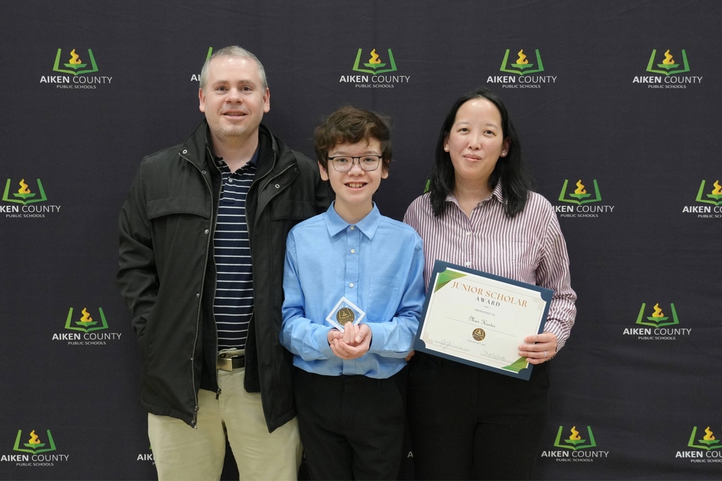 Student holding commemorative coin with family.
