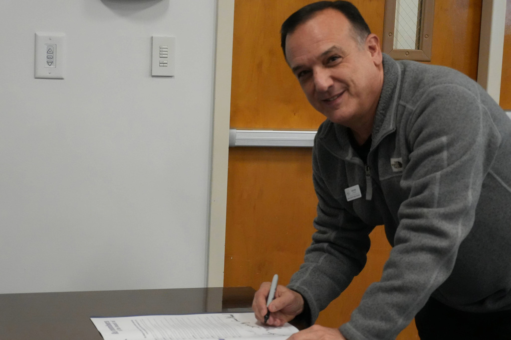 Board member smilibg while signing poster.