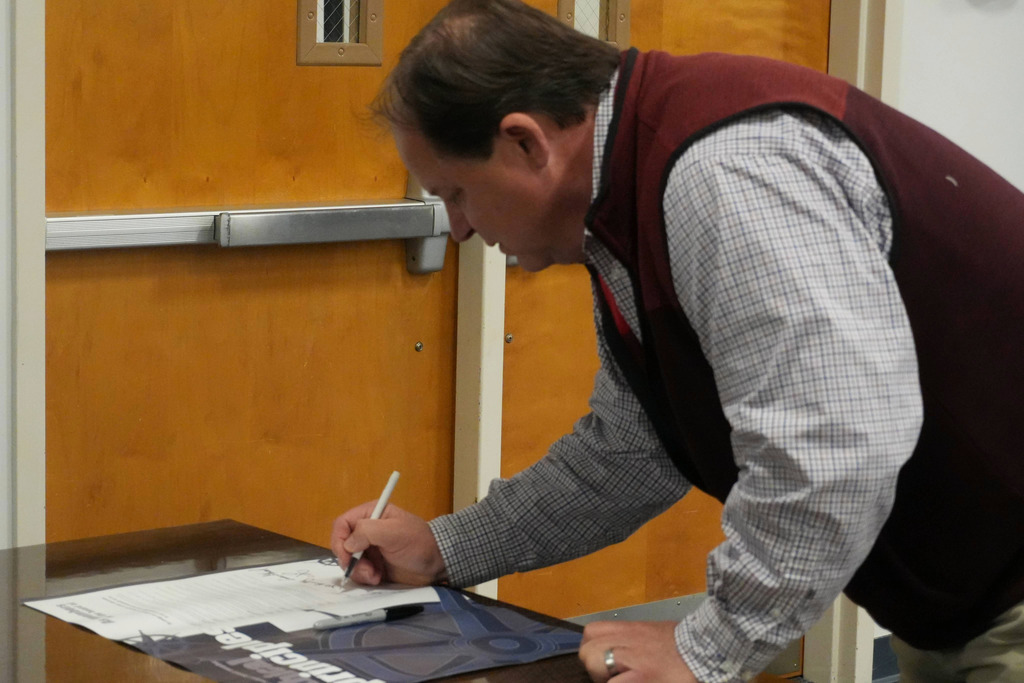 Board member signing poster with pen.