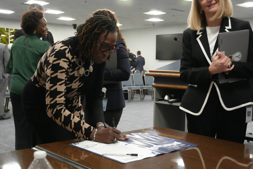 Board member signing poster with others.
