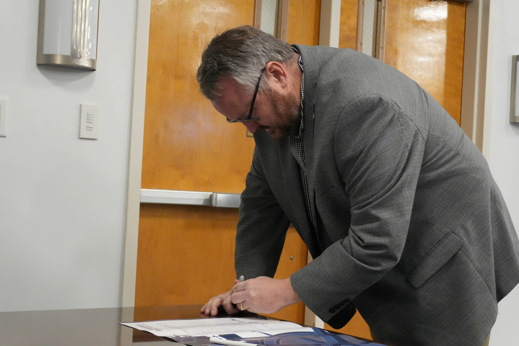 Board member signing poster.