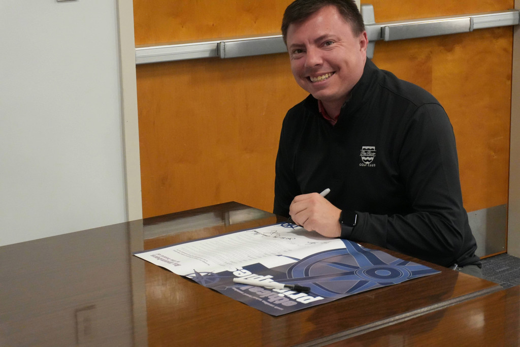 Board member smiling with poster.