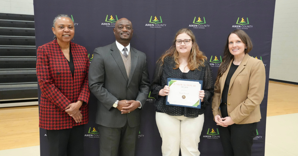 Student holding commemorative certificate with school administrators 