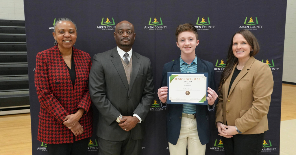 Student holding commemorative certificate with school administrators 