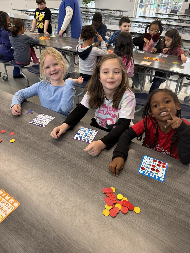three girls playing bingo in the school cafeteria