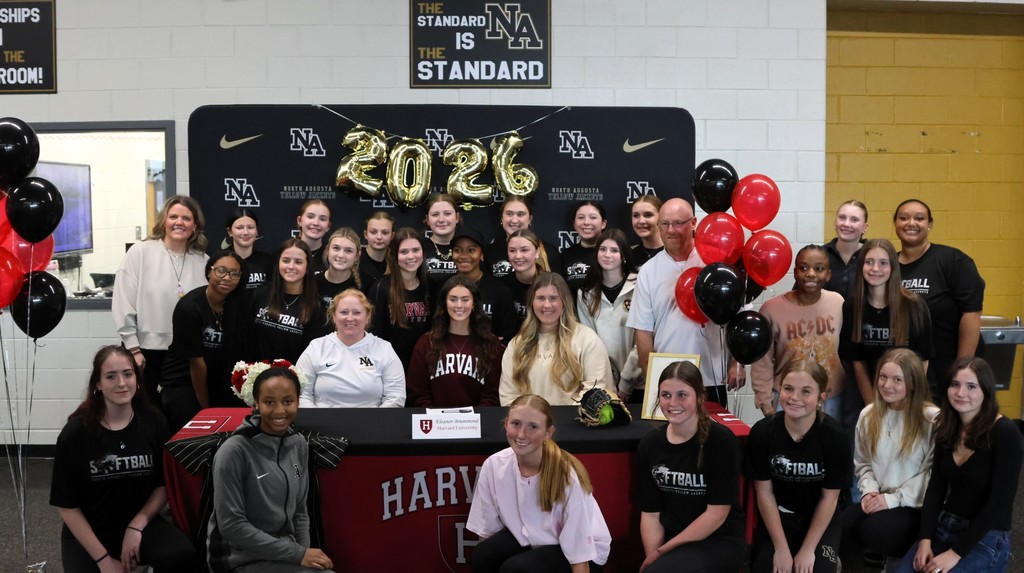 Group of students surrounding female softball player for Harvard University Signing. 