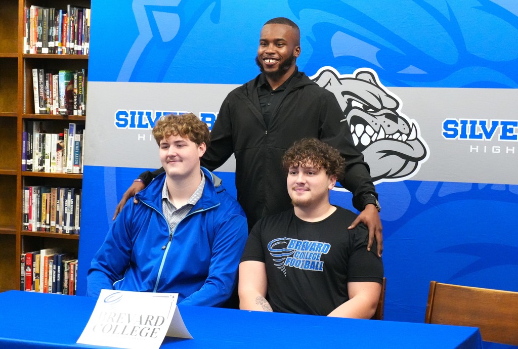 Adrian Gray and another student pose with a coach.