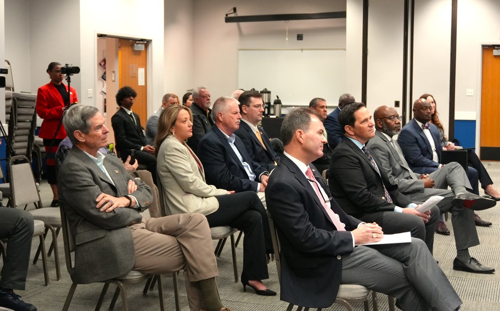 Education and political leaders listen to speakers.