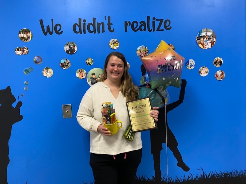 Ms. Amanda Gitchell holding an Employee of the Month Award.