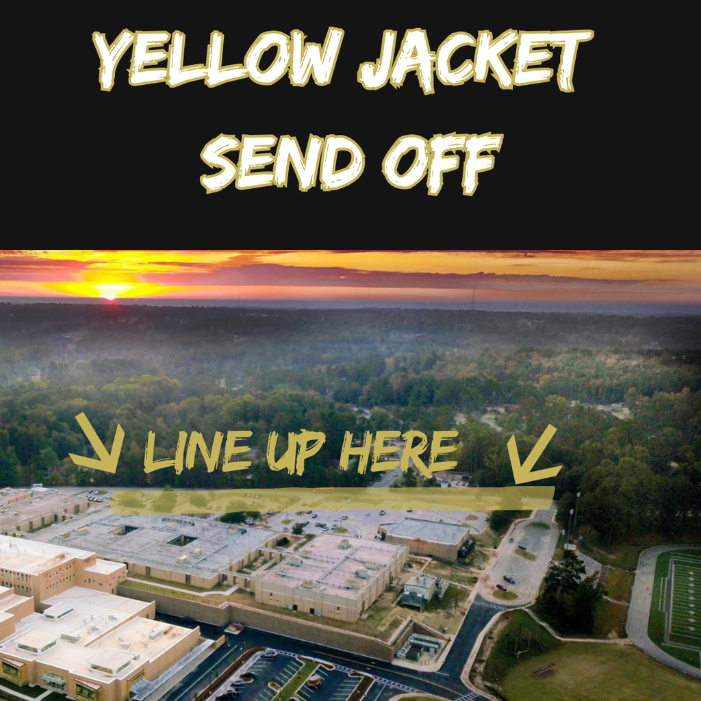 Picture of sunset with school in foreground and woods in background.