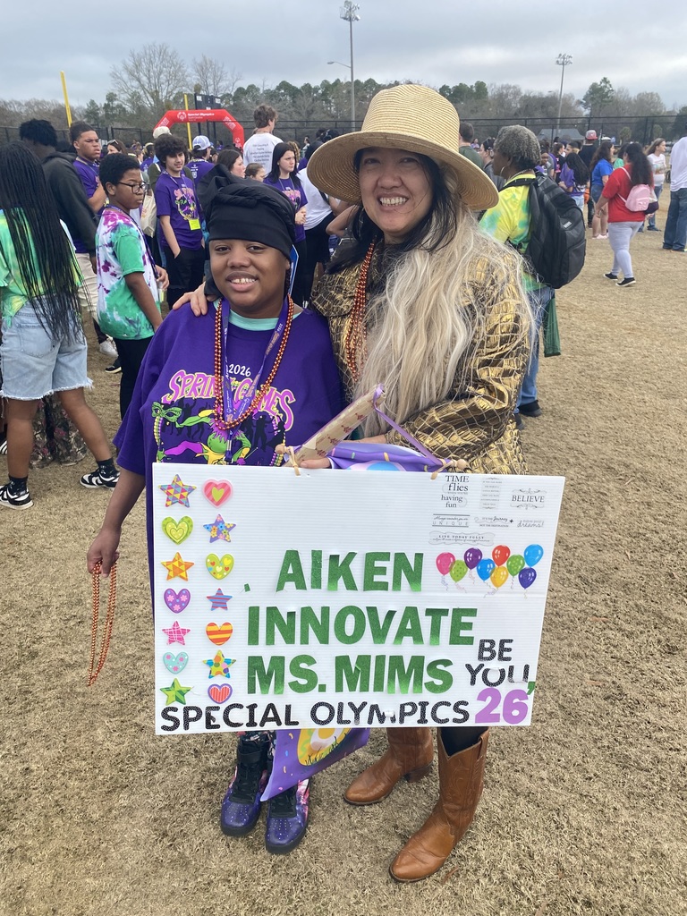 student and teacher holding a sign for Special Olympics