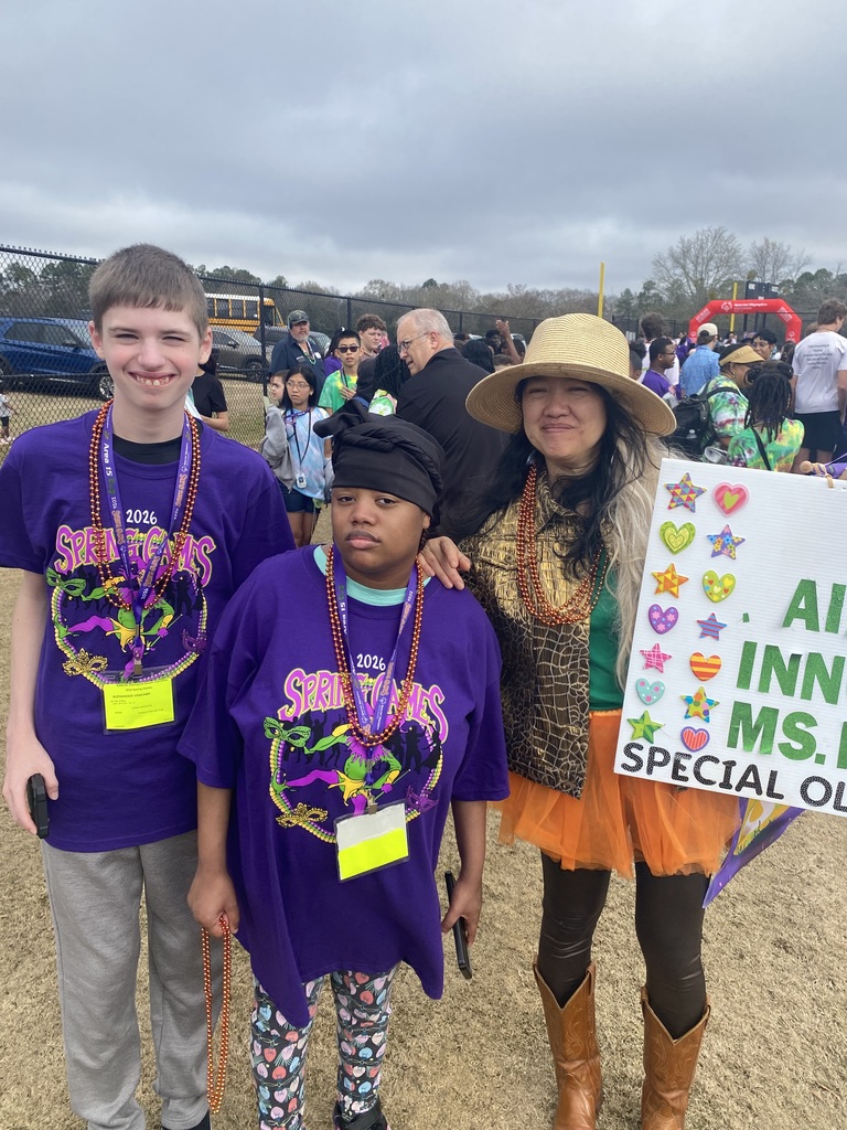 two students and teacher outside holding a sign
