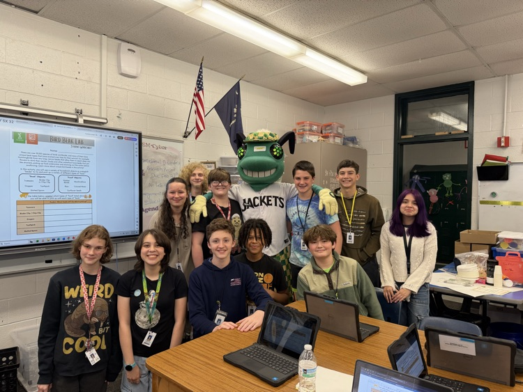 students posing with a baseball mascot that resembles a bug