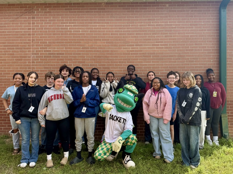 students posing with a baseball mascot that resembles a bug