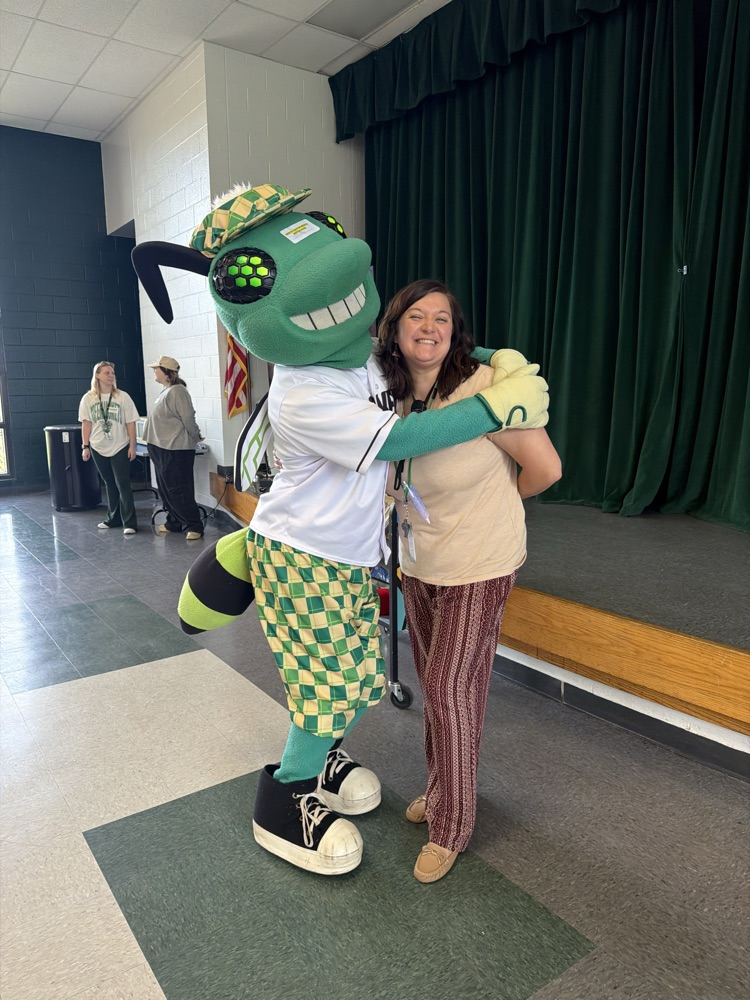 students posing with a baseball mascot that resembles a bug
