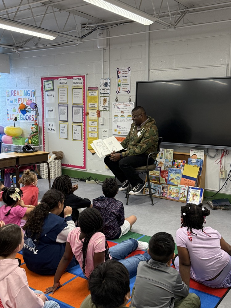Guest reader reading to 1st grade students.