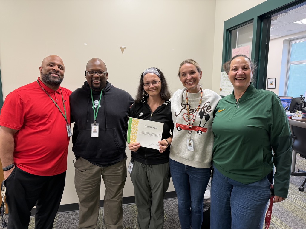 Ms. Ross holding a certificate with adminstrators around her. 