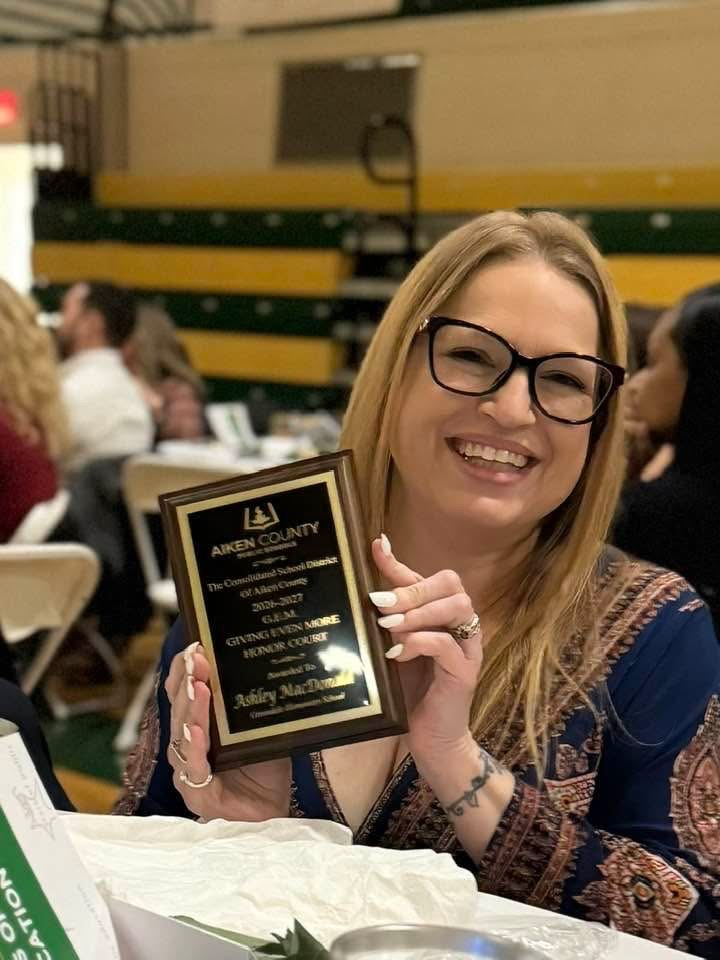 Ashley Macdonald posing with her GEM honor court plaque