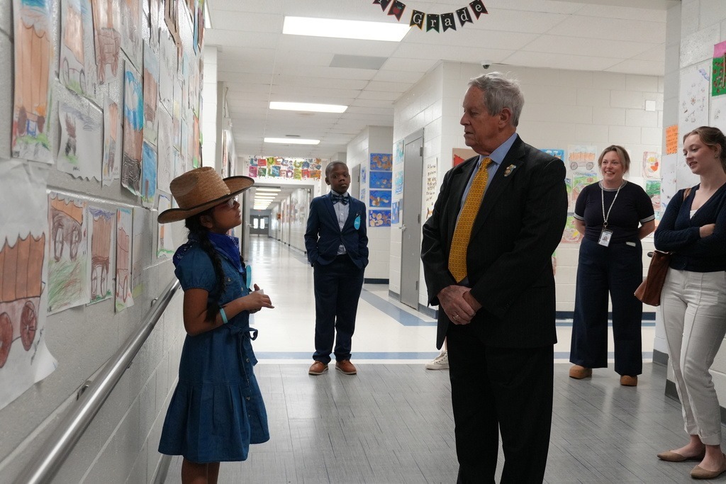 Congressman of South Carolina talking with elementary student in cowgirl outfit.