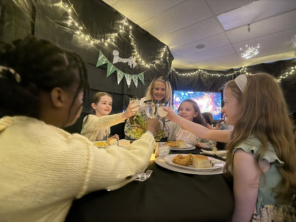 Teacher clinks glasses with group of students.