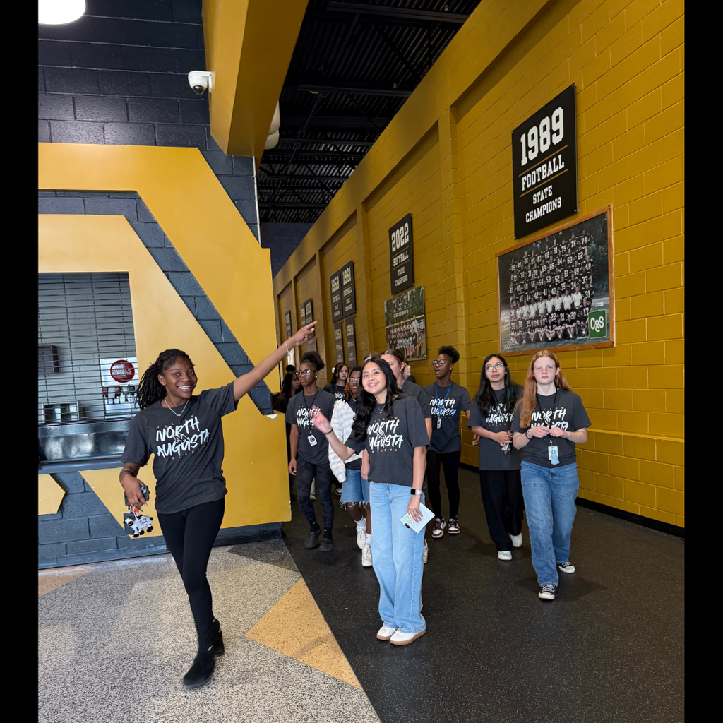 Students walking in gym hallway with leading student.