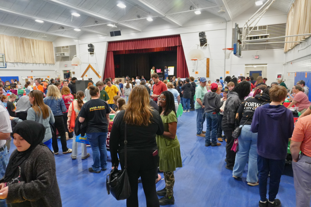 Room full of boothes, staff, and families participating in events and games.