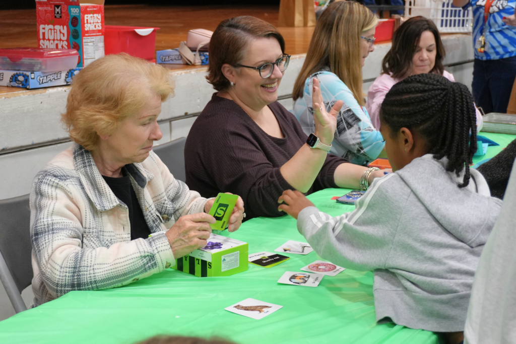 Two staff members playing vocab card game with student.