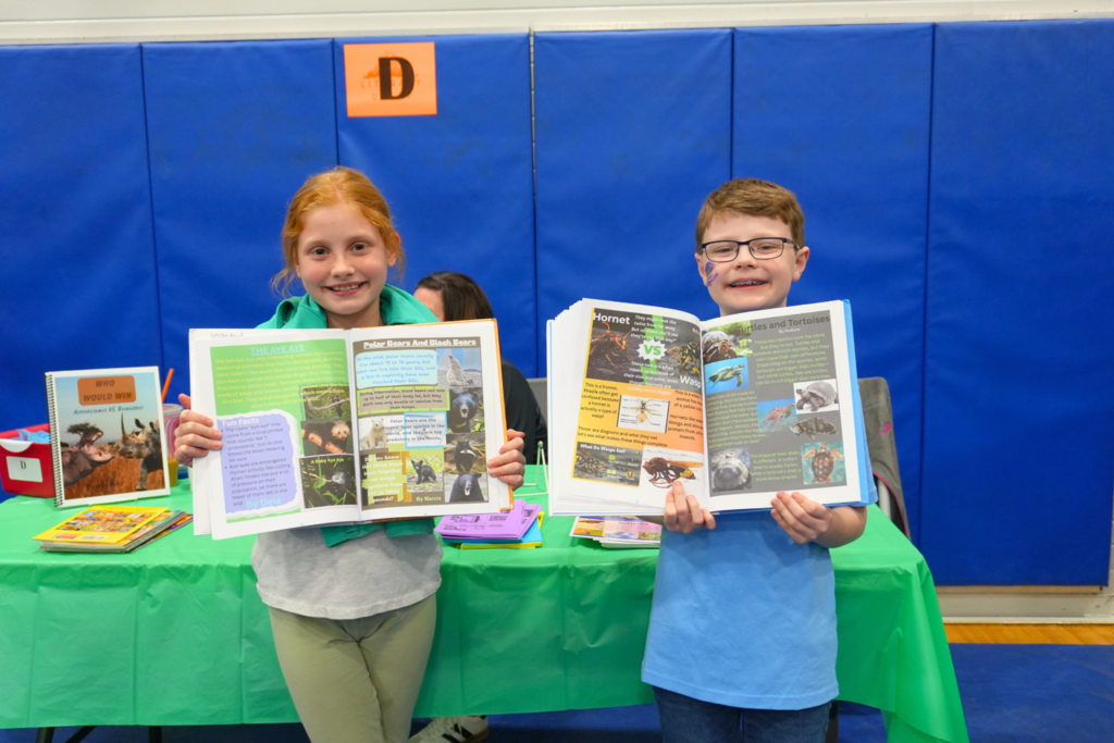 Two students holding books they wrote and put together.