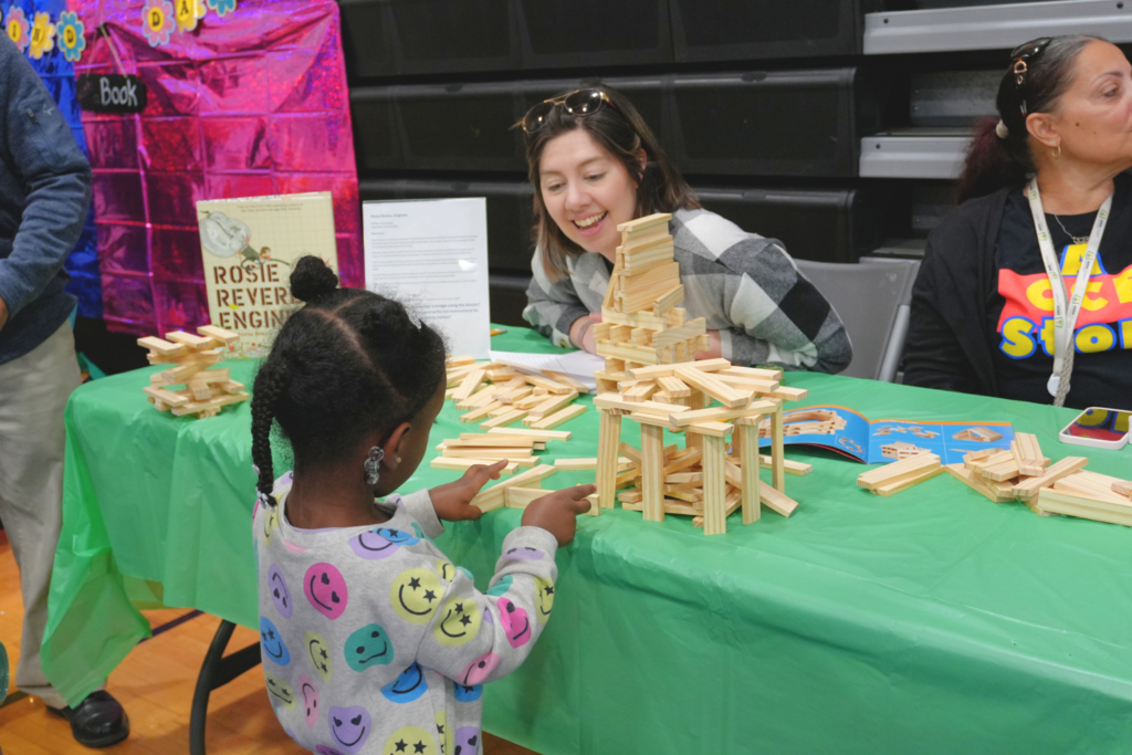 Student playing with wood blocks to make structure at engineering booth.