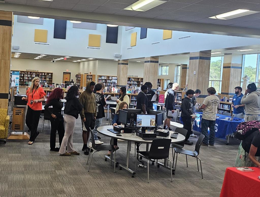 Students talking with colleges in library.