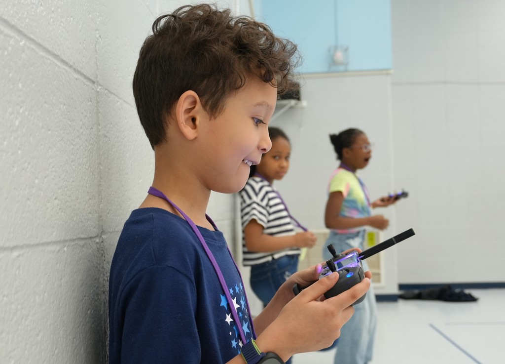 students holding remotes to drones. 
