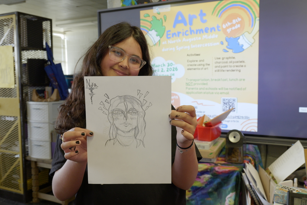 Student holding a sketch that she drew at Art Enrichment Camp.