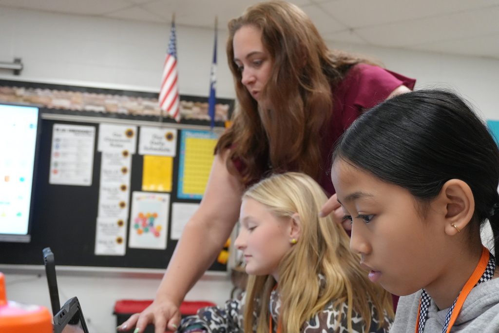 A Teacher showing a student how to do something on a screen.