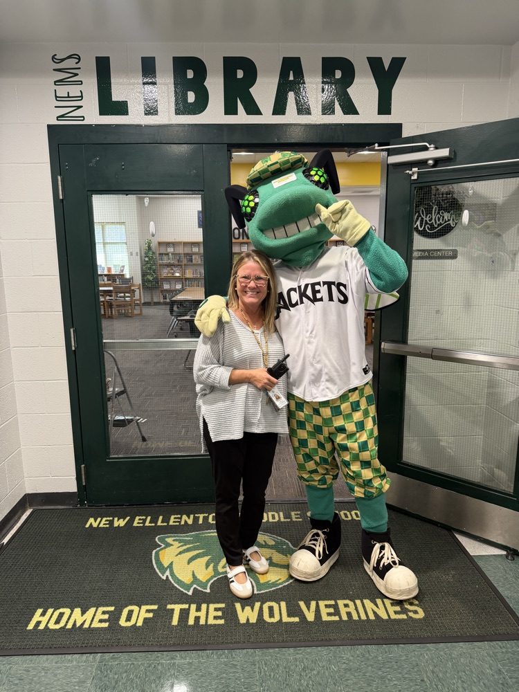woman posing with green jacket mascot 