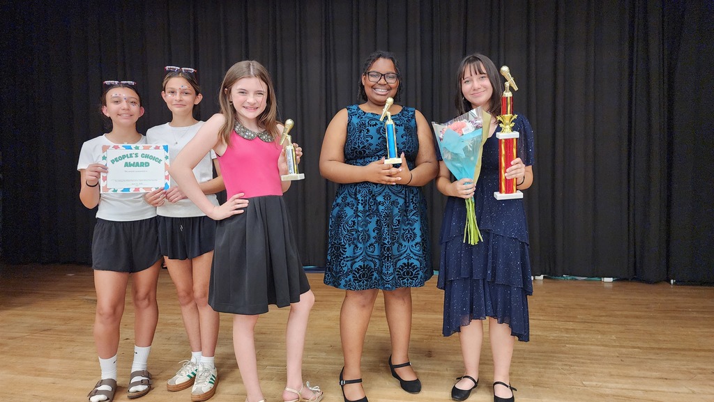 Students holding trophies on stage