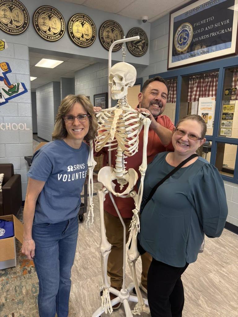 Three volunteers smiling with anatomy skeleton.