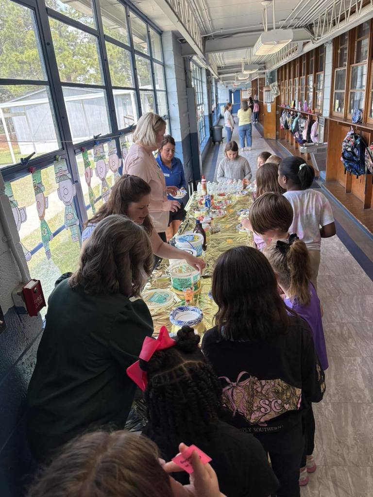 Volunteers at table serving students with icecream.