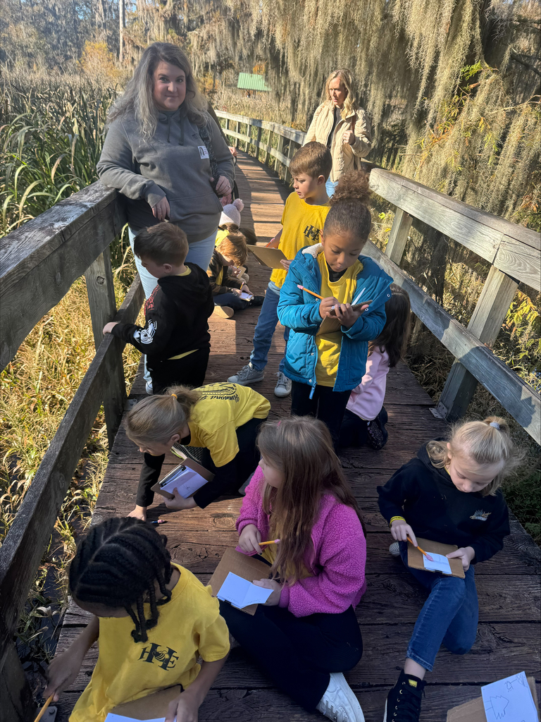 Two volunteers watching over students painting in the park.
