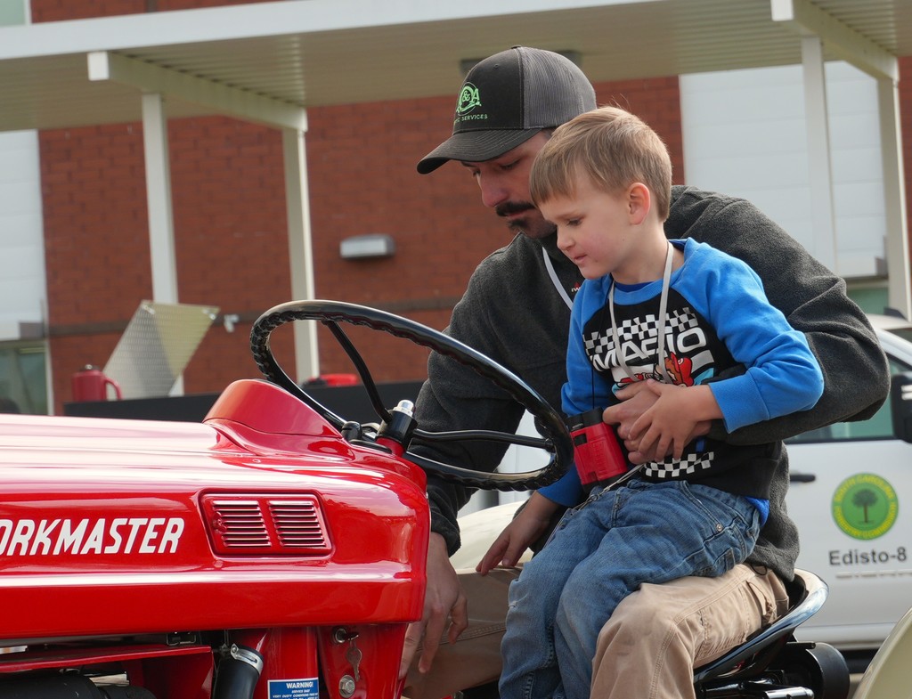 Parent sitting on tractor with child.