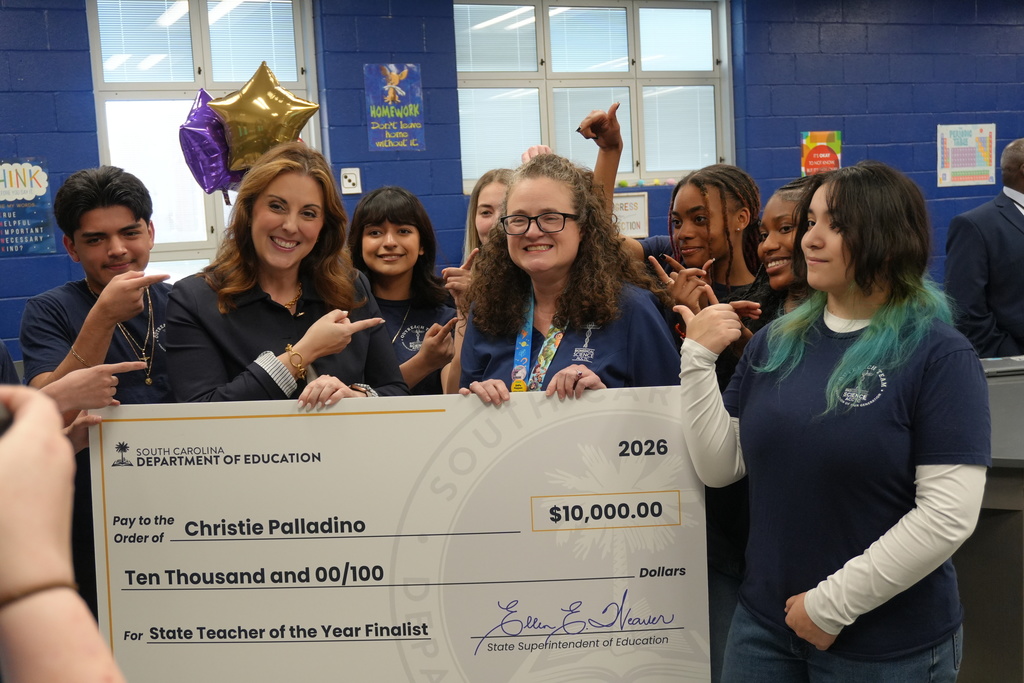 Dr. Christie Palladino being posing for photo with $10,000 check with her students.