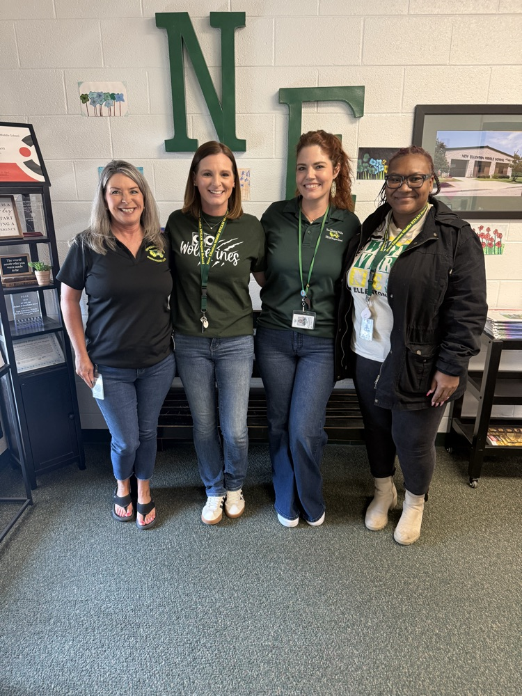 four women posing for a picture in the front office of a school 