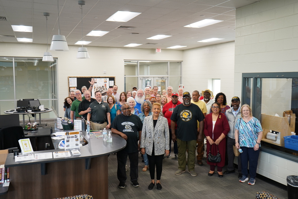 Class of '76 high school reunion attendees in a library. 