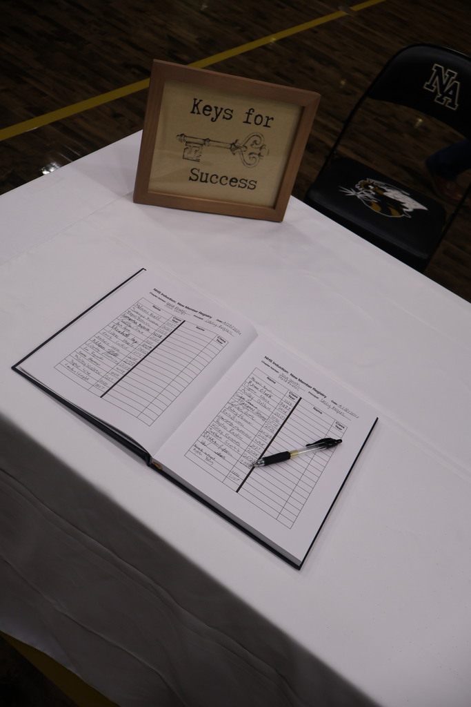Plaque of NHS Keys to Success and Book registry with pen on table.