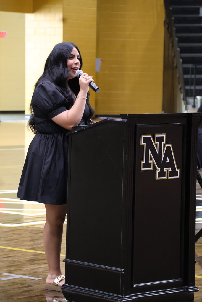 Girls standing at podium talking in gym.