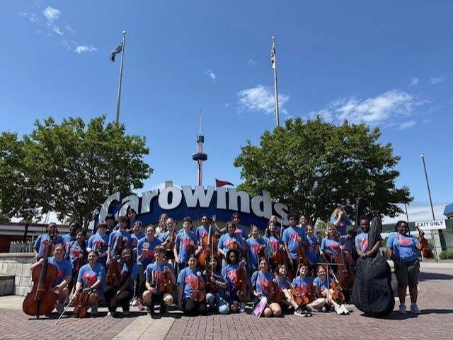 7th and 8th grade orchestra students in front of the Carowinds sign